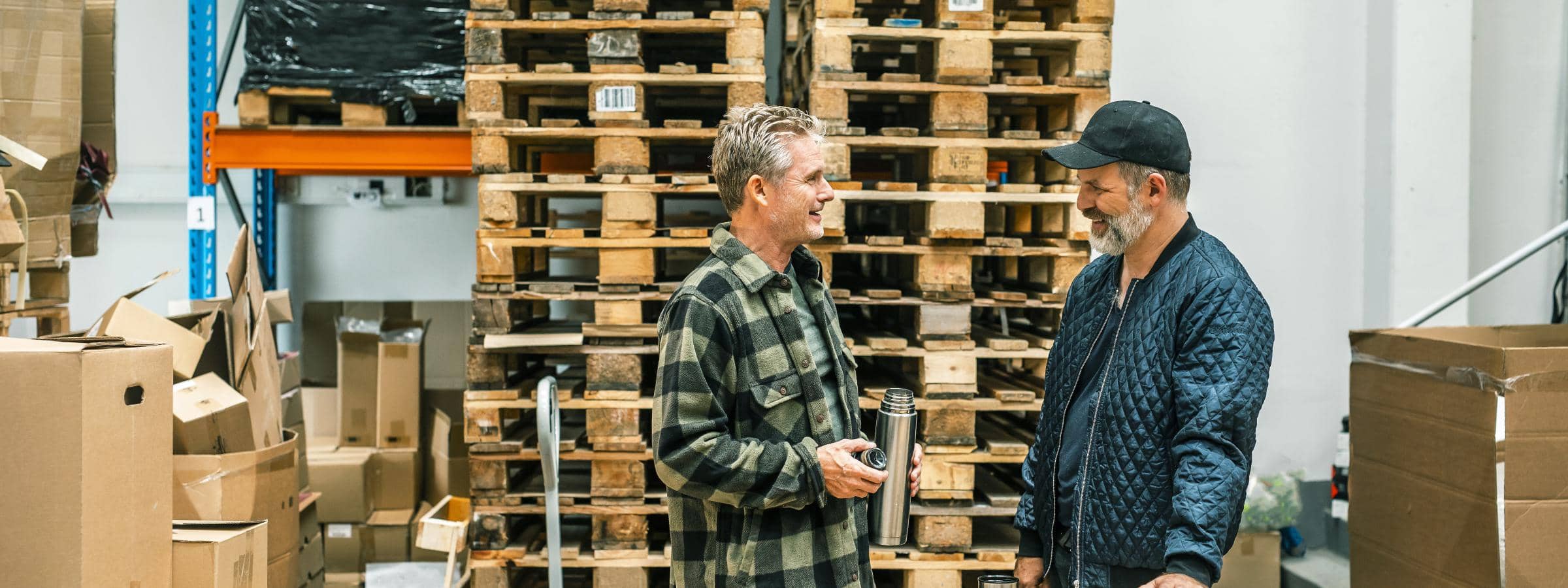 To mænd står på et lager og taler sammen