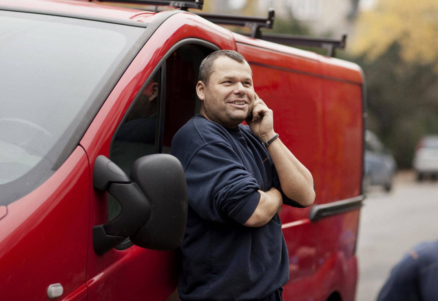 Varebilforsikring, mand snakker i mobil foran sin røde varevogn