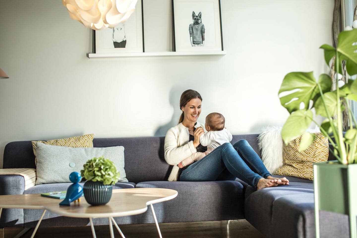 Kvinde der hygger med sin baby på sofa, nyder fordele der skaber tryghed i familien