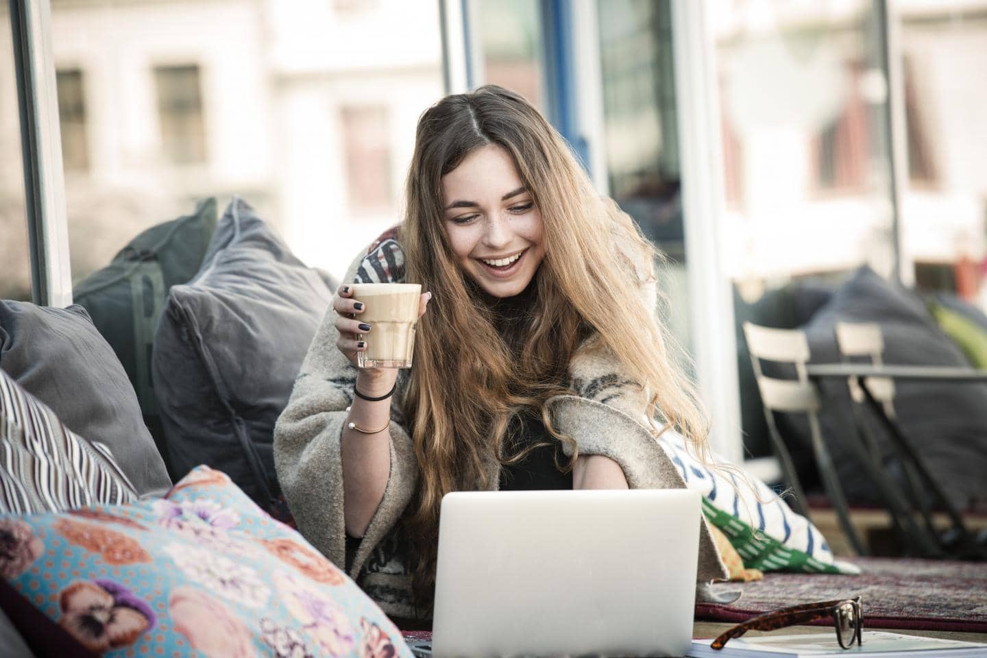 Ung pige som nyder en kop kaffe mens hun tjekker sine forsikringer online