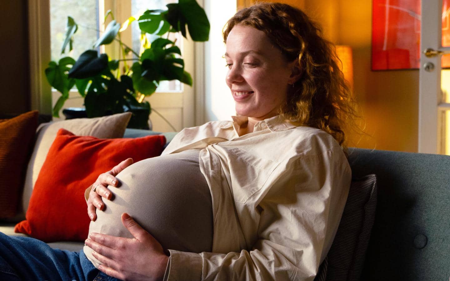 gravid kvinde sidder i sofa og holder om sin mave