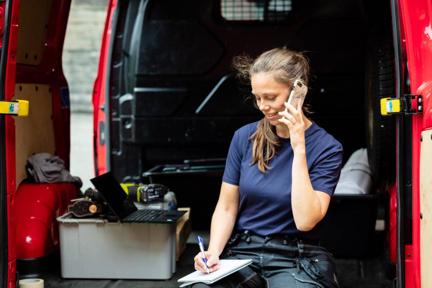 Kvinde taler i telefon med kunde i sin varebil