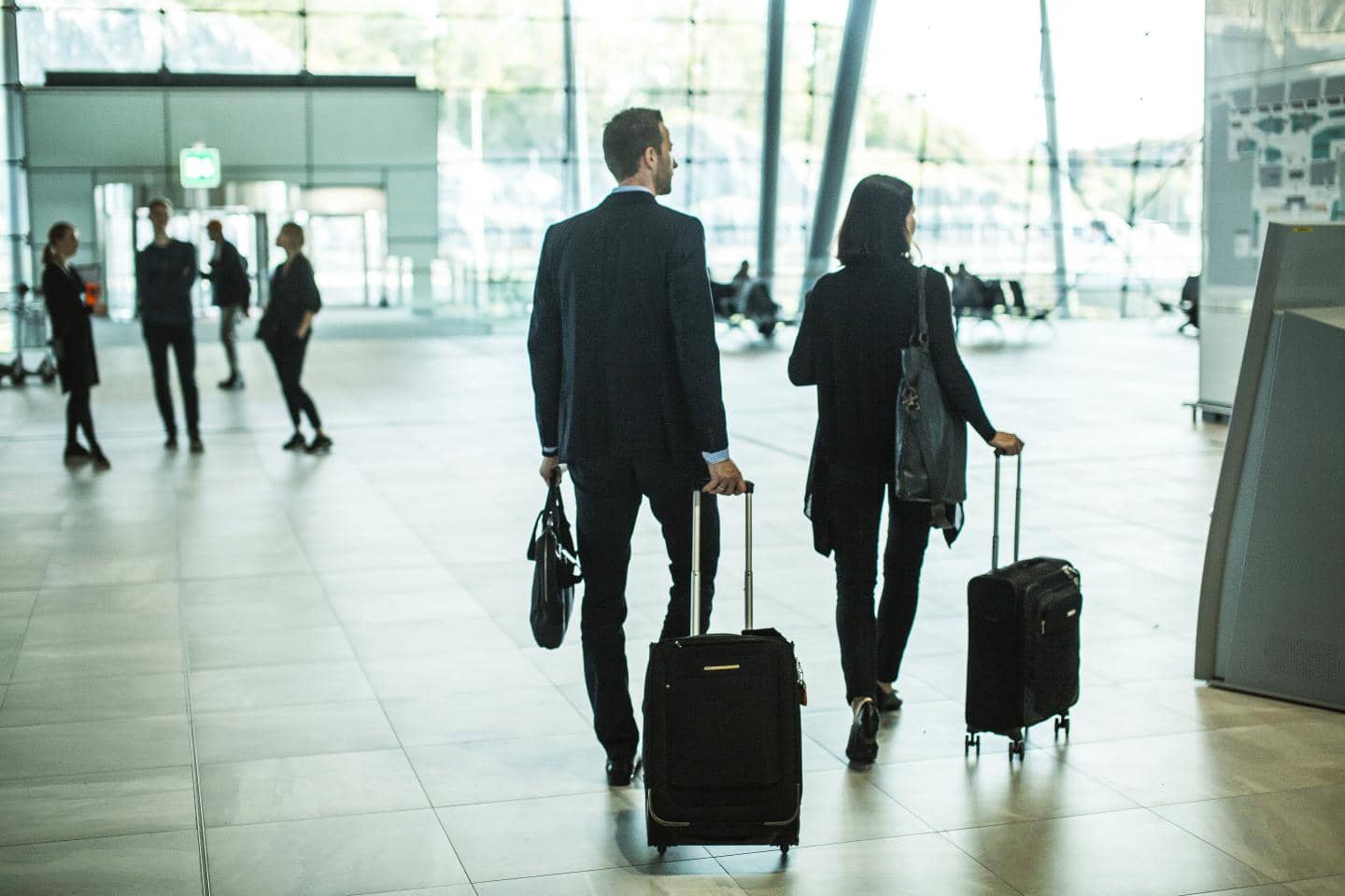 En kvinde og en mand i en lufthavn med en sort kuffert hver