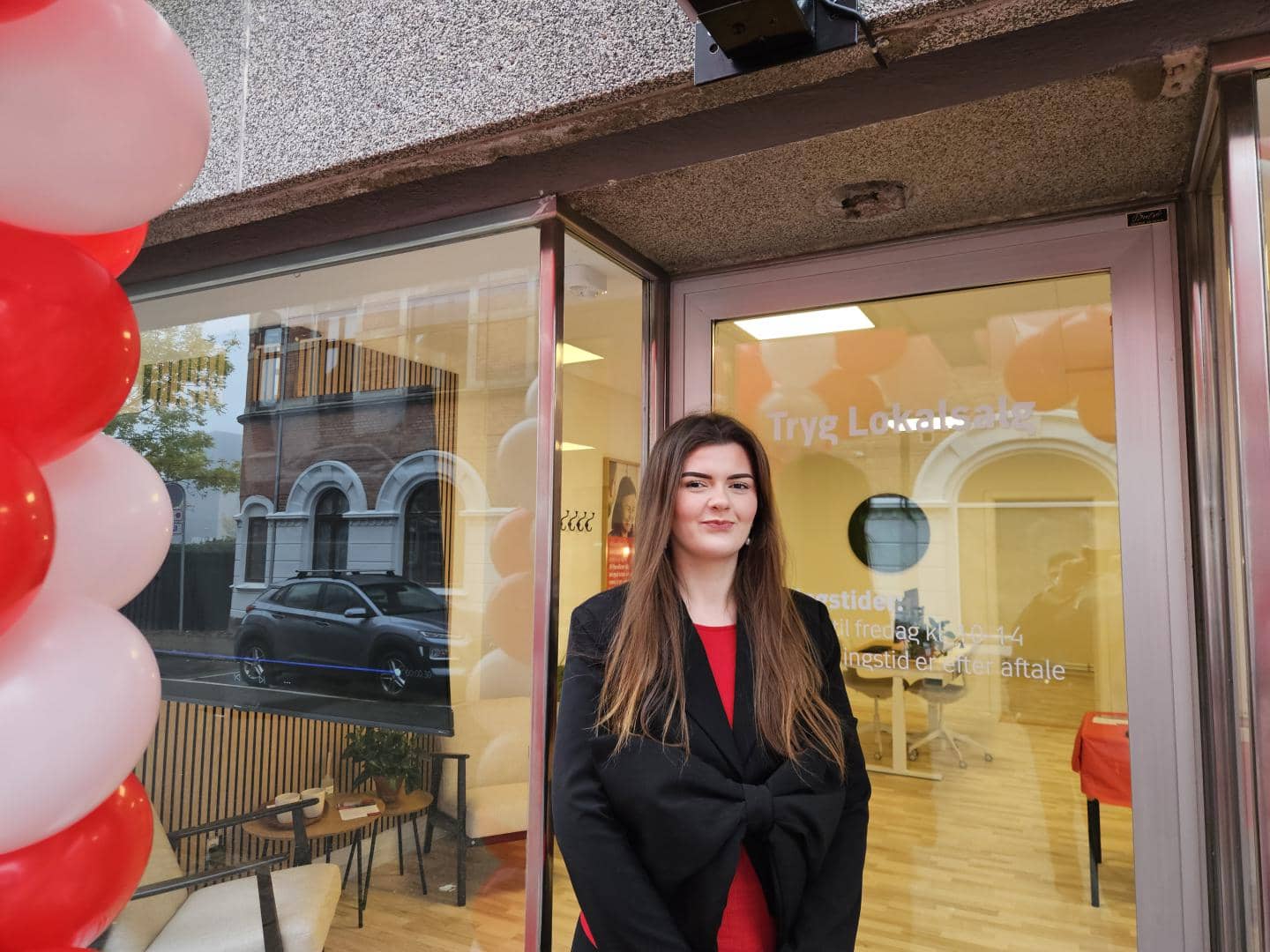 Kvinde står foran butik og smiler, fotografi