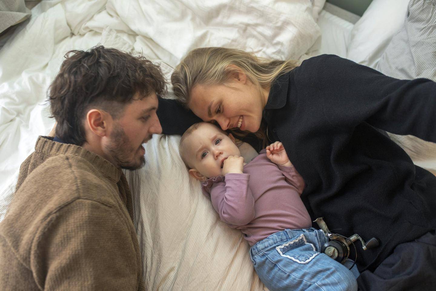 Småbørnsfamilie ligger sammen, fotografi
