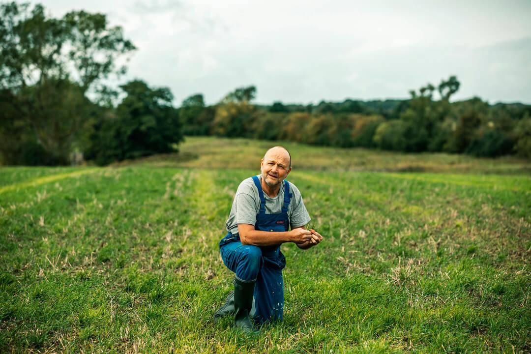 Johan, en landbrugsassurandør fra Tryg, på gårdbesøg på en grøn mark for at rådgive om landbrugsforsikring.