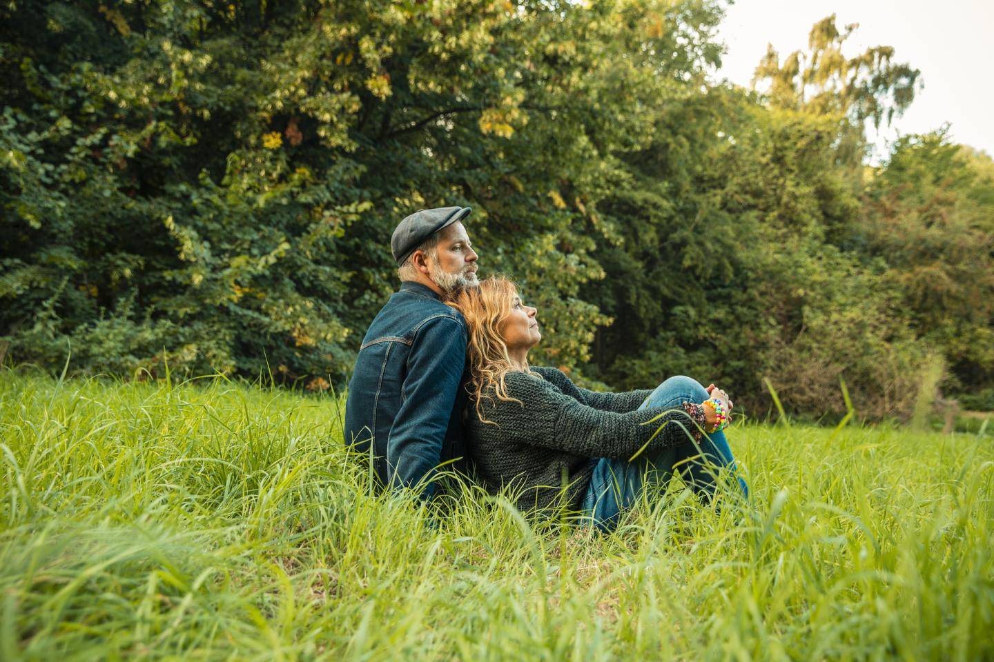 Par sidder i højt græs og nyder udsigt, fotografi