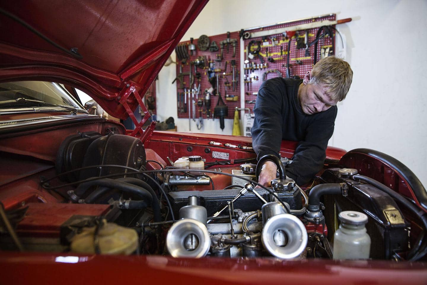 Tryg Reparationsværksted - mekaniker ordner motoren på en rød bil
