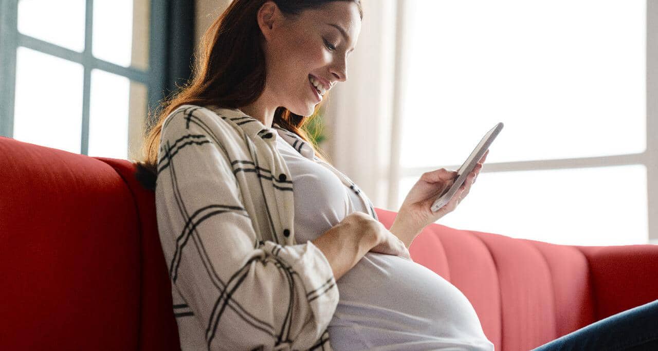 Gravid kvinde smiler til sin mave